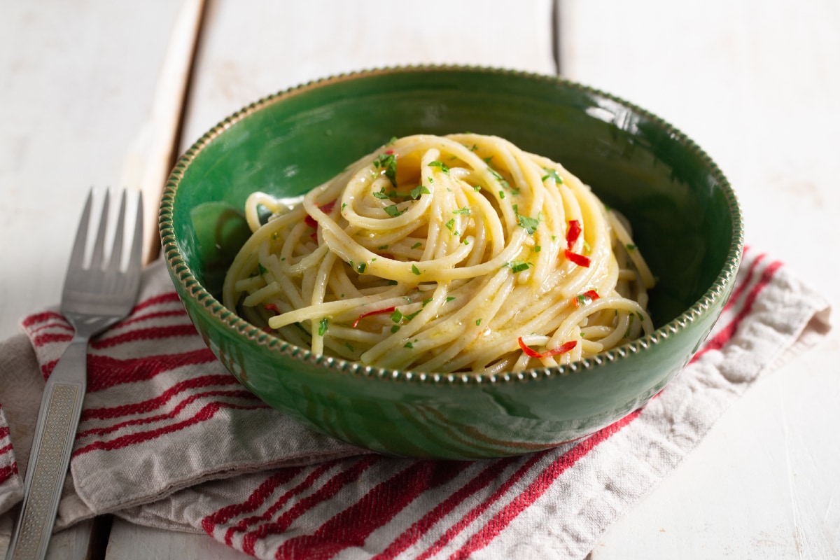 Seporsi spaghetti aglio olio dengan bawang putih dan cabai, disajikan hangat dengan taburan peterseli segar yang memberikan aroma harum khas Italia